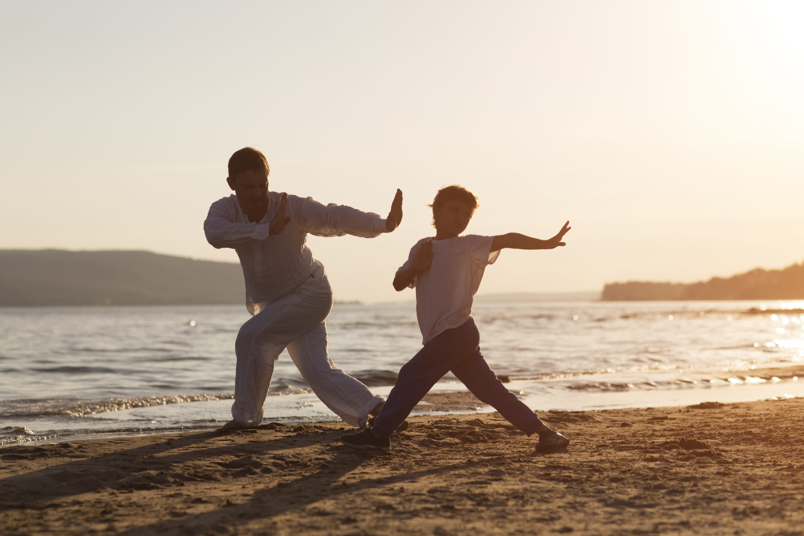 Family dad and son preschool child practice Tai Chi Chuan in the summer on the beach. Chinese management skill Qi's energy. solo outdoor activities. Social Distancing. family exercising together